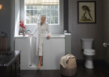 older woman wearing a robe walking out of a walk in tub