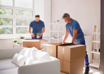 2 movers boxing up belongings for a move